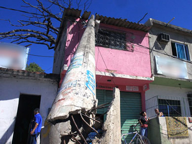 Poste da rede eltrica cai sobre casa em rua da Mangueira